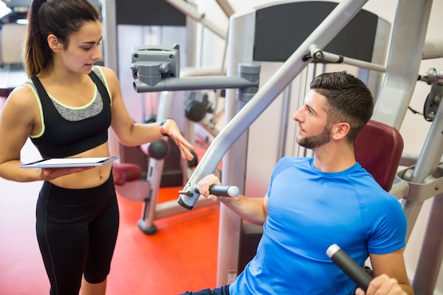 Trainer, der mit Athleten an der Gewichtsmaschine arbeitet