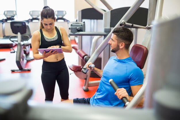 Trainer, der mit Athleten an der Gewichtsmaschine arbeitet