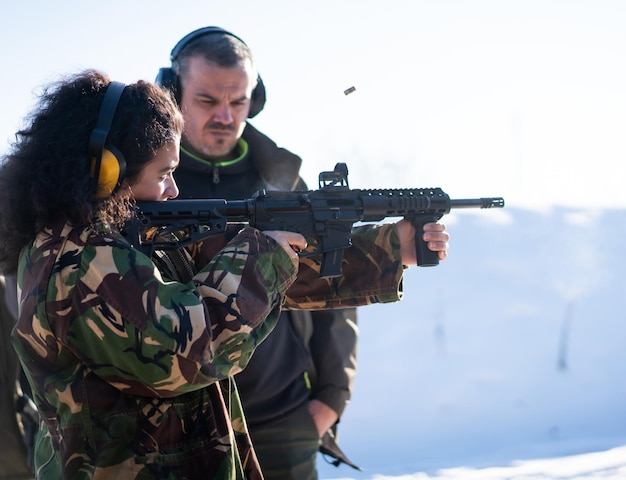 Trainer hilft jungen Frauen beim Kampftraining mit der Pistole zu zielen. Foto in hoher Qualität