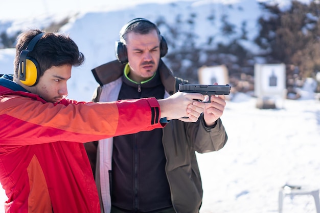 Trainer hilft jungen Menschen beim Kampftraining mit der Pistole zu zielen. Foto in hoher Qualität