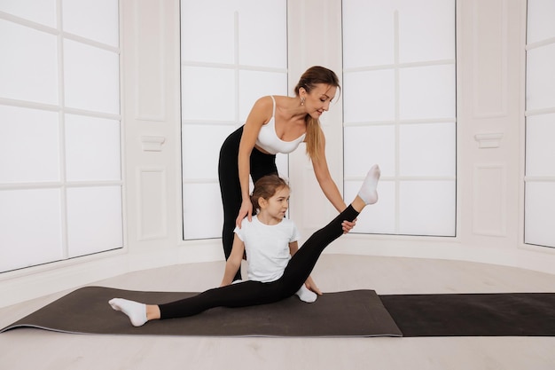 Trainer unterrichten und helfen kleinen Mädchen, die Pilates-Sport-Gymnastikübungen machen