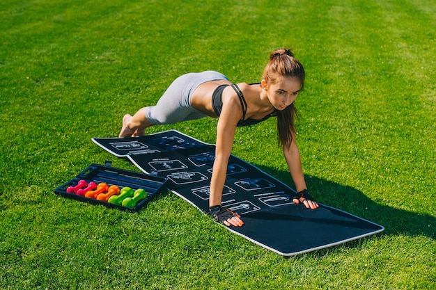 Trainieren der jungen Frau. Geeigneter sportlicher Brunette, der eine Planke auf Yogamatte tut. Gesunder Lebensstil und Sportkonzept.