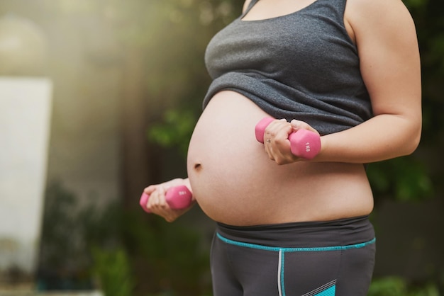 Trainieren mit einem Baby an Bord Schnappschuss einer nicht erkennbaren schwangeren Frau, die draußen trainiert