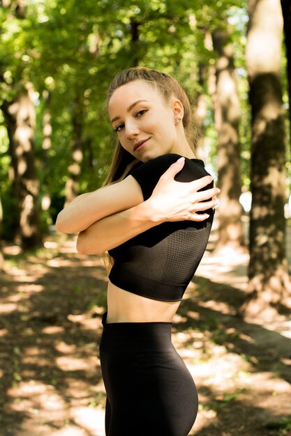 Training der jungen Frau vor der Fitness-Trainingseinheit im Park. Gesunde junge Frau, die draußen aufwärmt. Sie streckt den Rücken