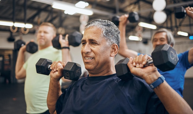 Trainingsgruppe und Senioren trainieren gemeinsam im Fitnessstudio Gewichte mit Hanteln für Kraft zu heben Ältere Alte und Fitness-Leute trainieren in einem Sportverein für Wellness und Gesundheit