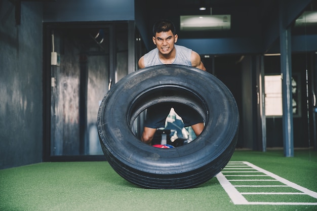 Trainingskonzept; Übendes Training des jungen Mannes in der Klasse; Gefühl von Engagement und Geduld beim Gewichtheben mit großen Reifen