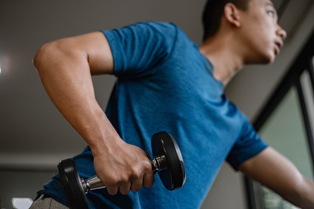 Trainingsstudiokonzept ein junger Erwachsener, der seinen muskulösen starken Arm verwendet, der eine Hantel im Fitnessstudio nach oben und unten hebt.