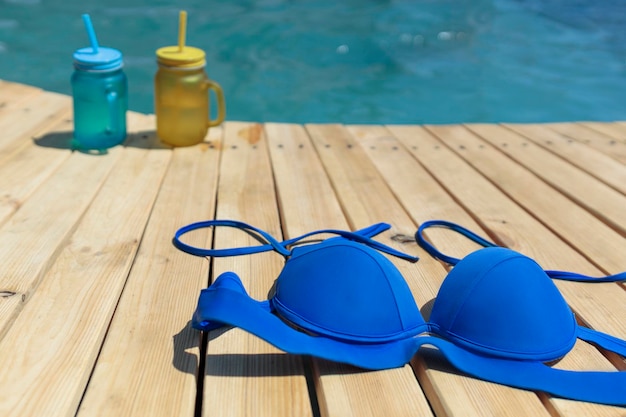Traje de baño y dos cócteles de color amarillo y azul junto a la piscina Fiesta en la piscina al aire libre