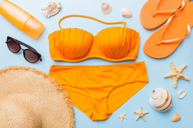 Traje de baño de mujer y accesorios de playa vista superior endecha plana sobre fondo de color Concepto de viaje de verano bikini traje de baño sombrero de paja y seasheels Espacio de copia Vista superior