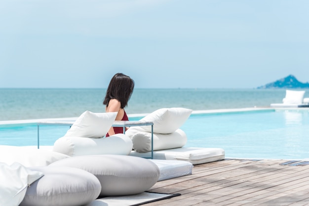 Traje de baño de la mujer en la cama blanca en el mar de la playa de la piscina