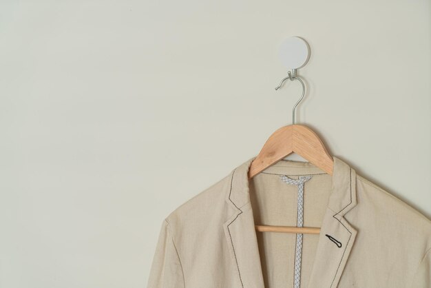 traje beige colgado con percha de madera en la pared