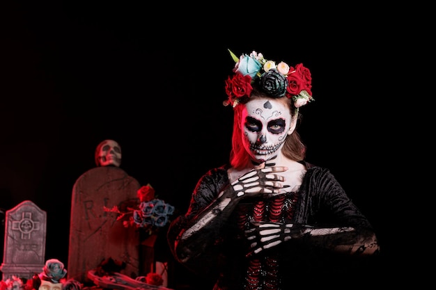 Traje de diosa de la muerte de la dama del horror con arte corporal, con corona de flores para celebrar la fiesta tradicional mexicana de dios de los muertos. Mujer con calavera de santa muerte maquillada en estudio.