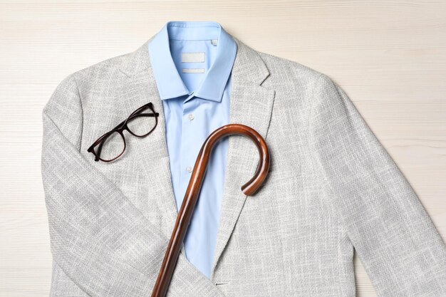 Foto traje elegante con bastón sobre fondo blanco de madera endecha plana