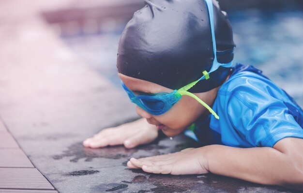 Traje húmedo, niño asiático con gafas de natación, nadar en una piscina.