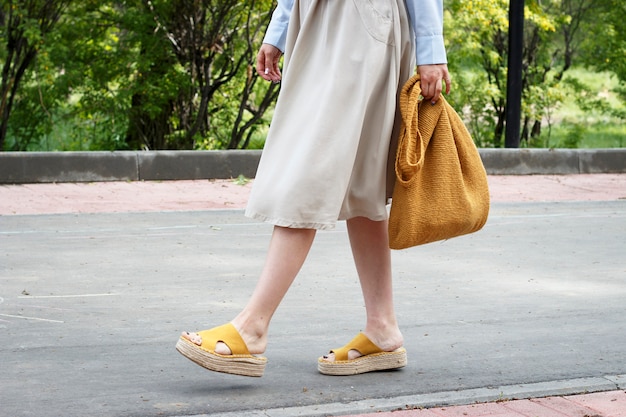Traje de moda de verano. Chica en vestido, zapatos amarillos y bolso de punto de moda, vista lateral