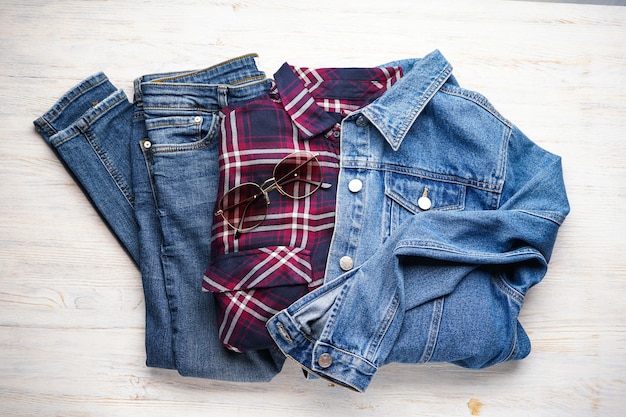 Trajes casuales de mujer con ropa de jeans sobre una superficie de madera, endecha plana.