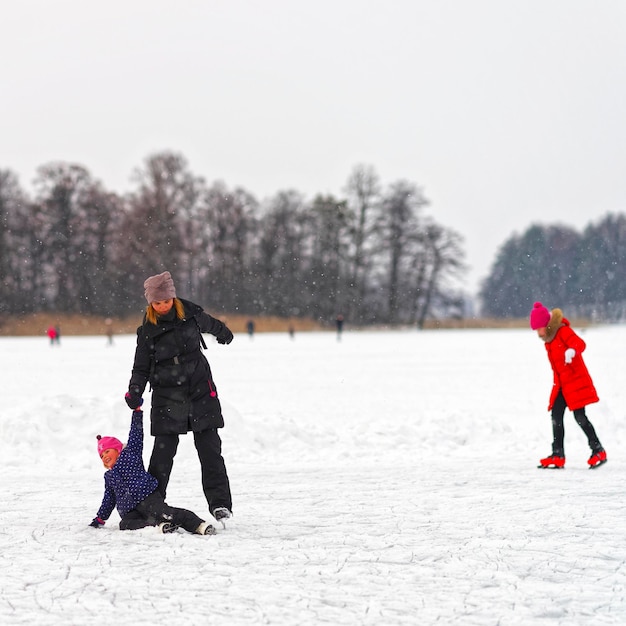 Trakai, Lituânia - 17 de janeiro de 2016: Criança caindo enquanto patinar no gelo com a mãe na pista. A patinação envolve qualquer atividade que consiste em viajar no gelo usando patins