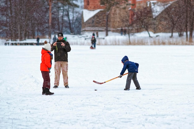 Trakai, Lituânia - 17 de janeiro de 2016: Crianças jogando hóquei no gelo na pista no inverno Trakai. O hóquei no gelo é um esporte de equipe de contato jogado no gelo, geralmente em uma pista.