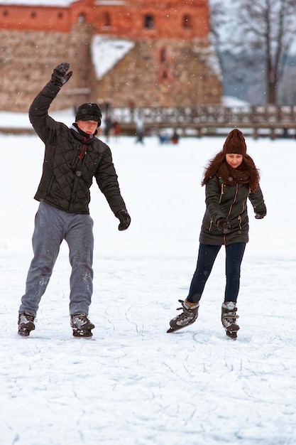 Trakai, Lituânia - 17 de janeiro de 2016: Jovem casal patinação no gelo no rinque coberto de neve Trakai. A patinação envolve qualquer atividade que consiste em viajar no gelo usando patins. Foco seletivo