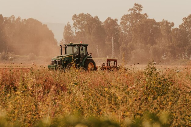 Foto traktor auf dem feld gegen bäume