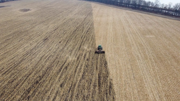 Traktor, der den Boden pflügt und über einen grünen Traktor fliegt, der nach der Ernte den Boden im gelben Feld pflügt