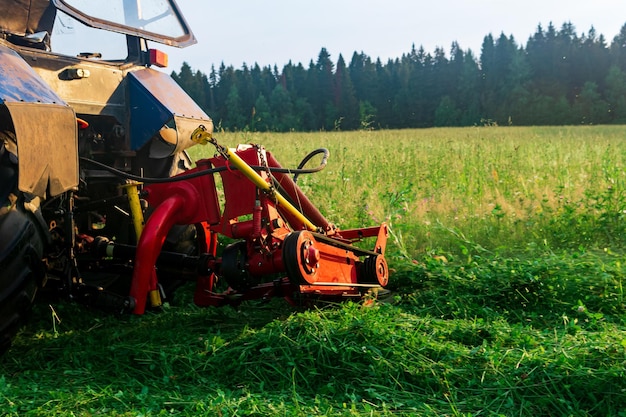 Traktor mit montiertem Mäher mäht Wiesenstauden