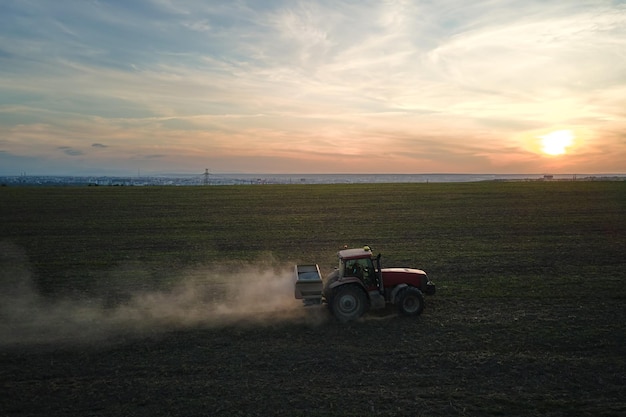 Traktor sprüht Düngemittel mit Insektizid-Herbizid-Chemikalien auf landwirtschaftlichen Feldern bei Sonnenuntergang