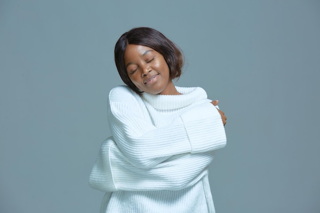 Tranquila y bonita mujer afroamericana abrazarse sonriendo amor propio cuerpo de autocuidado