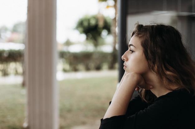 Tranquila chica adolescente bonita en el balcón mirando hacia otro lado