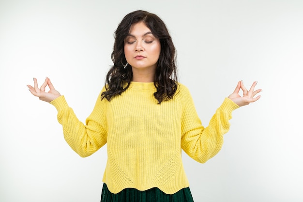 Tranquila chica morena con un suéter amarillo y falda verde atrapa a zen