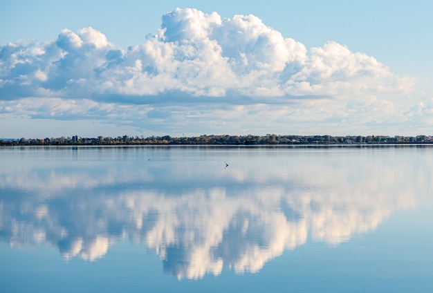 tranquila laguna, nubes y una iglesia en la distancia