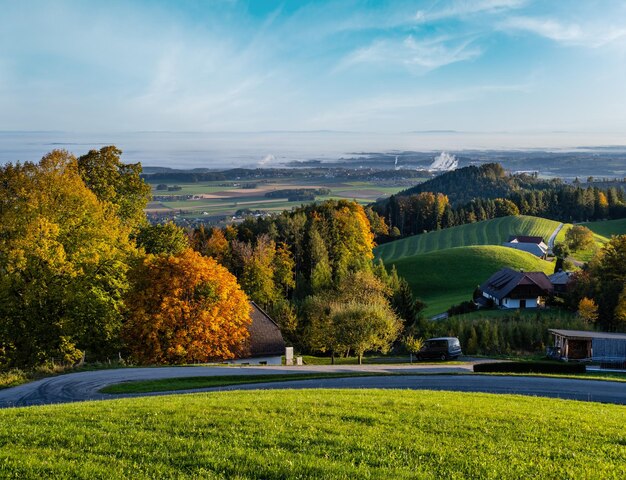 Tranquila mañana soleada de otoño vista rural desde Gmundnerberg con campo brumoso en la lejana Austria