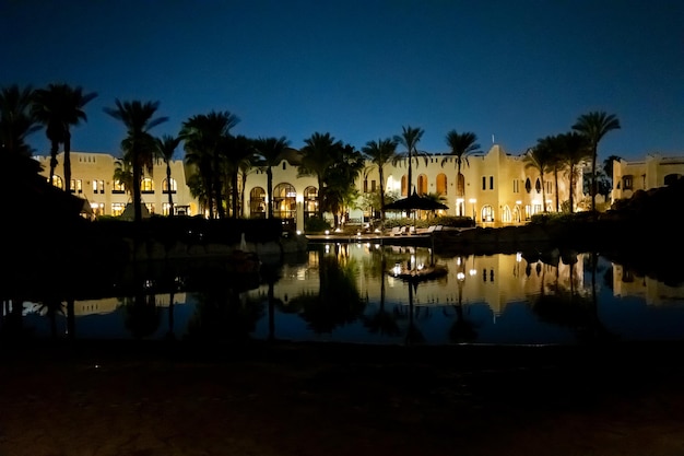 Tranquila vista serena de las palmeras del hotel de la piscina por la noche