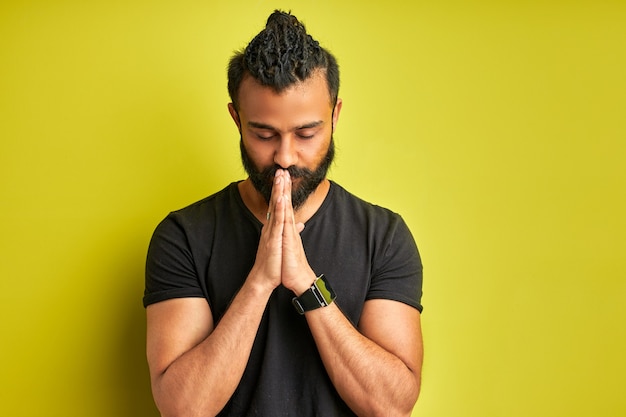 Foto tranquilo chico árabe ora aislado sobre fondo verde en estudio