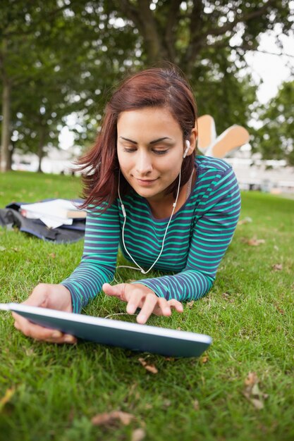 Tranquilo estudiante casual tumbado en la hierba con tableta