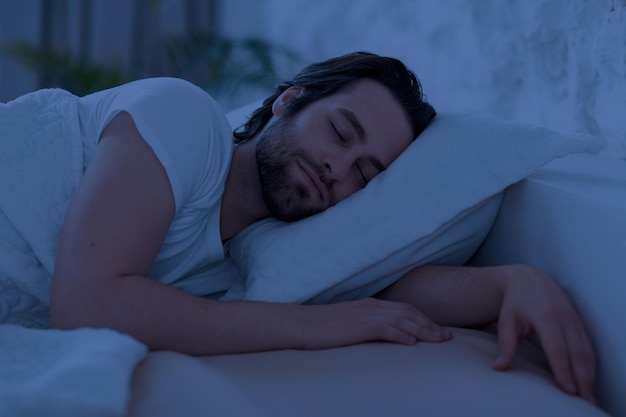 Tranquilo joven durmiendo en la cama solo en casa