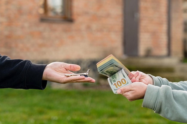 Transfira dinheiro e chave para casa na frente de casa imóveis mudando para casa ou alugando o conceito de propriedade