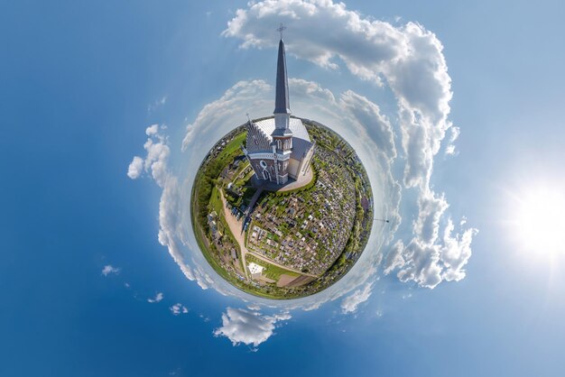 Transformación del pequeño planeta del panorama esférico de 360 grados con vistas a la iglesia en el centro del globo en el cielo azul Vista aérea abstracta esférica con curvatura del espacio