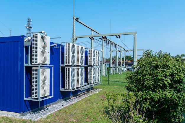 Foto transformator-kraftwerk mit großen kühlventilatoren an der hinteren wand blauer himmel und grüne büsche