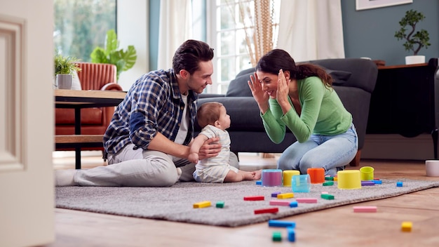 Transgender-Familie mit Baby-Spiel mit bunten Spielzeugen in der Lounge zu Hause