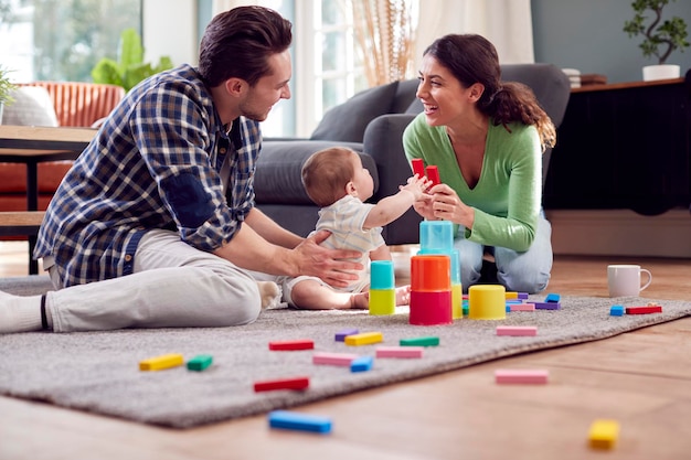 Transgender-Familie mit Baby-Spiel mit bunten Spielzeugen in der Lounge zu Hause