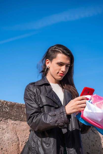 Transgender-Frau konsultiert ihr Smartphone mit der Trans-Flagge im Freien LGTBIQ-Aktivismus