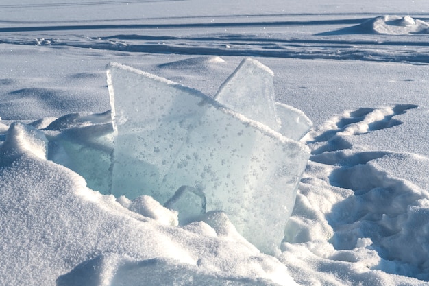 Transparente blaue Eisschollen, die an einem sonnigen Tag in Eishügeln vor blauem Himmel aufgetürmt sind. Ungewöhnliche Winterlandschaft des zugefrorenen Baikalsees. Natürlicher kalter Hintergrund. Sibirien, Russland.