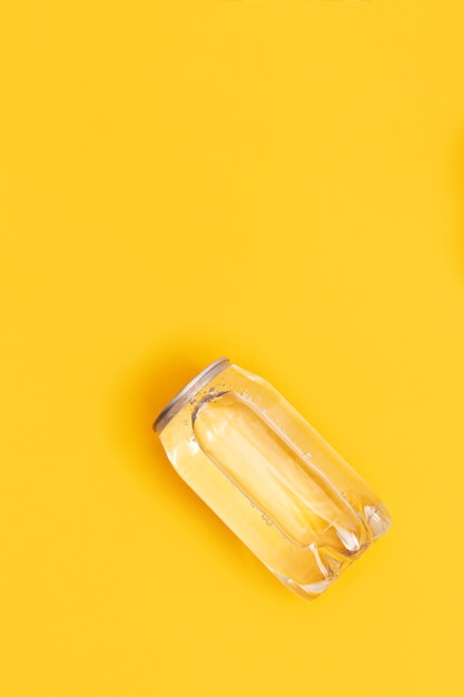 Transparente Dose Wasser auf gelber Oberfläche