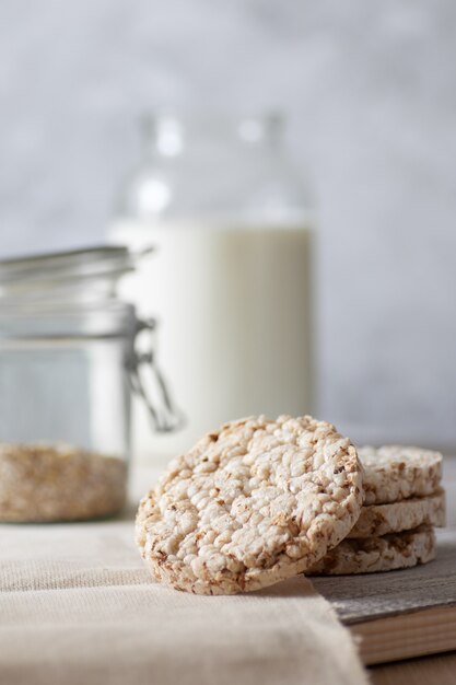 Transparente Dosen Milch und Müsli, Vollkorn-Knäckebrot auf einem Holztisch auf einem Grau