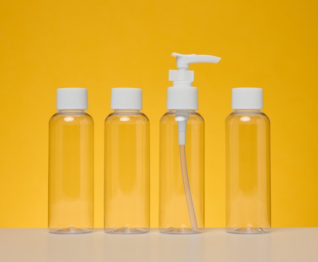 Transparente Plastikflaschen für flüssige Kosmetik auf gelbem Hintergrund