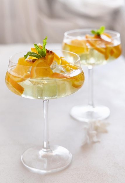 Transparenter Cocktail mit Eiswürfeln in einem mit Orangenscheiben verzierten Glas aus nächster Nähe