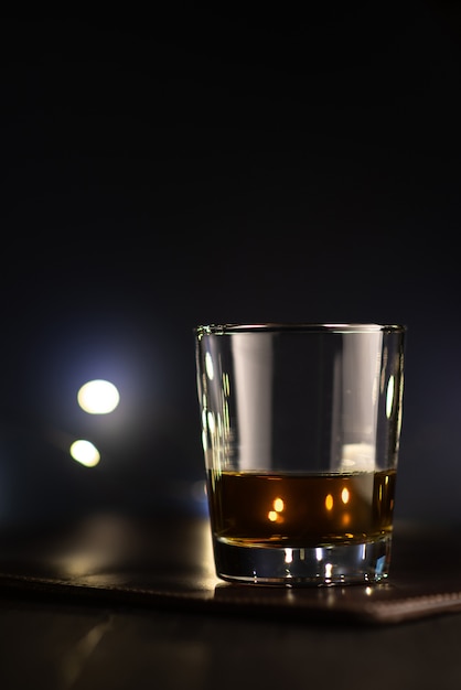 Transparentes Glas mit Whisky auf einem Lederständer