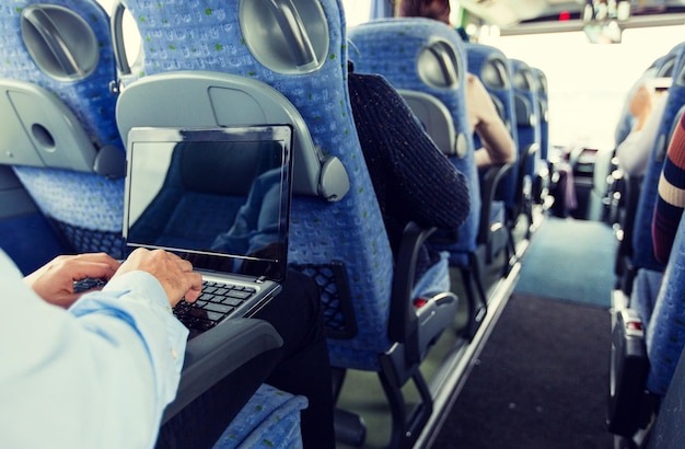 Transport-, Tourismus-, Geschäftsreise- und Personenkonzept - Nahaufnahme eines Mannes mit Laptop, der im Reisebus tippt