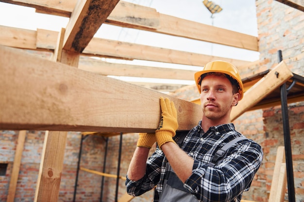 Transport von Holzbrettern Bauarbeiter in Uniform und Sicherheitsausrüstung haben Arbeit am Bau